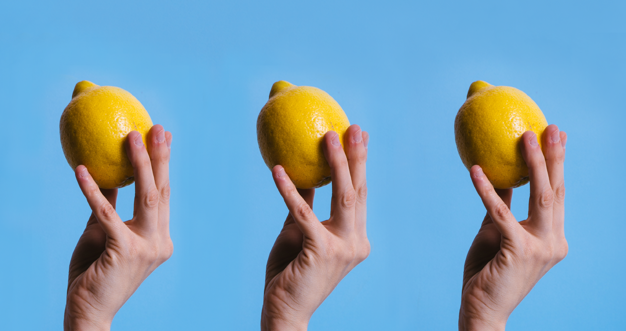 Three Hands Holding Three Lemons on a light blue background