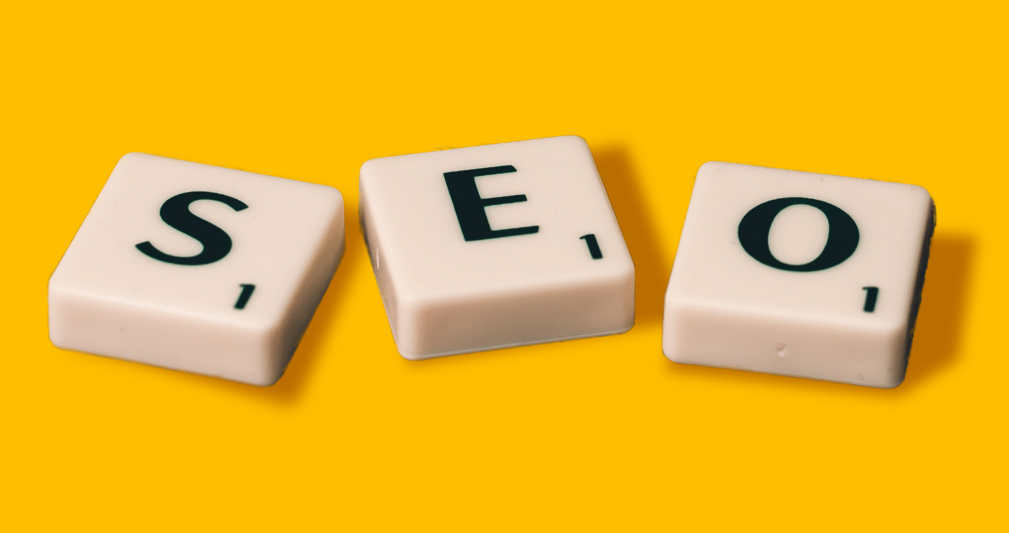 SEO - Letters in scrabble tiles on a yellow background