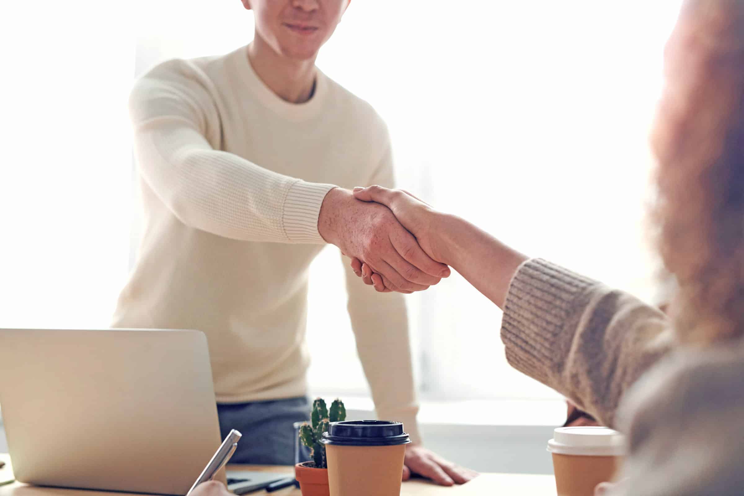 A man and a woman shaking hands at a desk, implying a deal has been made.